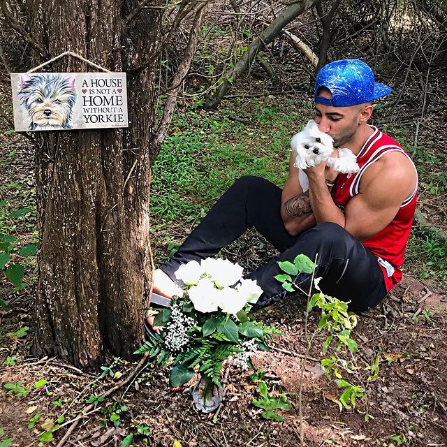 Yousef Saleh Erakat in a red dress and black pants kissing his lovely pet dog.